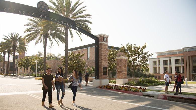 学生 walk near the Schmid gate on the Chapman campus